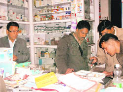 MC chief OP Uniyal (left) looks as forensic experts take finger prints at a shop in Mussoorie on Tuesday.