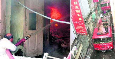 A firefighter douses flames at a box factory in Ludhiana on Saturday; and (right) fire engines have a tough time passing through the narrow street leading to the factory.