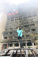 A youth takes photos of the burning building of the ruling National Democratic Party in Cairo