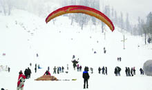 Tourists enjoy paragliding at Solang valley, 13 km from Manali, on Sunday.