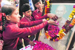 Schoolchildren sprinkle flower petals on a portrait of Mahatma Gandhi on his 63rd death anniversary, in Amritsar on Sunday