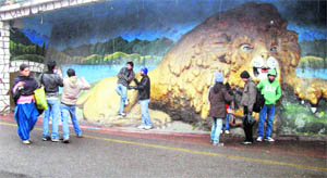 Tourists pose for a photograph while standing in front of the famous lion sculpture in Mussoorie.