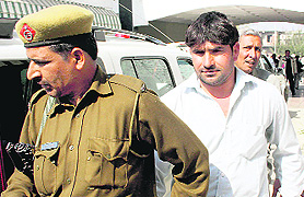 Amarjeet being taken away by a policeman from the Canal Rest House in Rohtak.