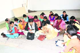 Students attend a class while sitting on the floor at Government College for Women in Rohtak