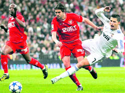 Real Madrid's Cristiano Ronaldo (R) is tackled by Sevilla's Sergio Sanchez in Madrid on Wednesday
