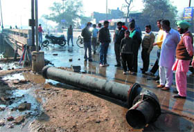 People look at a water pipe, that burst due to high pressure, near the Sirhind Canal bridge in Bathinda on Friday. The pipe was thrown nearly 20 feet high and fell on a passerby, Sushil Kumar, severing his leg.
