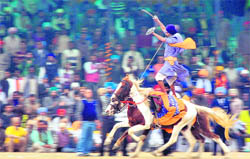A nihang shows his horse riding skills balancing two horses on Sunday.