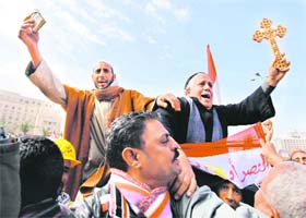 A Muslim holding the Koran (top left) and a Coptic Christian with a Cross at a rally of opposition supporters at Tahrir Square in Cairo