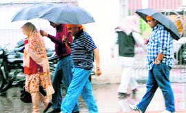 People use umbrellas to protect themselves as it rains in Amritsar on Monday.