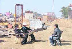WORKWHILE: Engineers of Soma Company sit idle at a site where work on widening of National Highway-I in Ludhiana was stalled a week ago.
