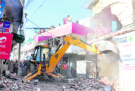 A JCB removes an illegal structure during a demolition drive at Hallo Majra in Chandigarh on Wednesday. 