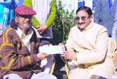 Chief Minister Ramesh Pokhriyal Nishank presents a cheque of Rs 4 lakh to ailing journalist and author Sudhir Thapliyal in Mussoorie. 