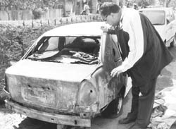 A man watches a burnt car at his residents in Sector 16, Panchkula,