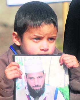 A boy holds a photograph of his missing father during a protest in Srinagar