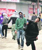 Youths throw stones at the police during a protest at Maisuma in Srinagar