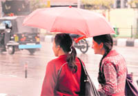 Girls try to protect themselves from the rain in Jammu on Sunday.