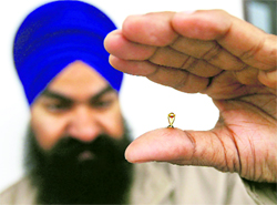 Miniature artist Gurmeet Singh shows a gold replica of the cricket World Cup he has made, in Amritsar on Sunday. The replica weighs 150 mg and has a height of 2mm.