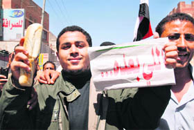 A Yemeni holds up a loaf of bread and a sign that reads in Arabic, Who is next during a protest  in the capital Sanaa on Sunday.