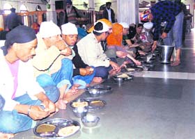 Devotees partake of langar in Sri Guru Ram Das Langar Hall in the Golden Temple complex