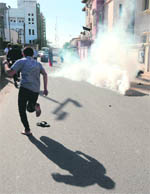 A Bahraini protester runs for cover after the police fired tear gas canisters to disperse demonstrators.