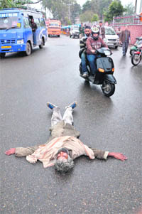 A man lies in an inebriated condition in the middle of a busy road in Jammu.