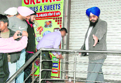 Shopkeepers, led by Narinder Singh Pappu, a trustee of the Ludhiana Improvement Trust (in blue turban), break the seal of a shop.