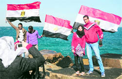 Egyptians pose for pictures with their national flag during a rally celebrating the success of the popular revolt at the northern port of Alexandria on Tuesday