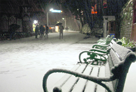 People walk during a snowfall on the Mall in Shimla