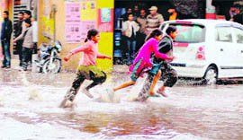 Children wade their way through a flooded road in Jammu on Wednesday