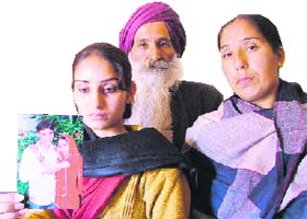 Manpreet Kaur, flanked by her parents, shows a picture of her engagement