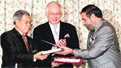 Commerce Minister Anand Sharma (R) exchanges a signed document with Malaysia's International Trade and Industry Minister Mustapa Mohamed (L) as Malaysia's Prime Minister Najib Razak witnesses during the signing ceremony of the Malaysia-India Comprehensive Economic Cooperation Agreement in Putrajaya, Kuala Lumpur