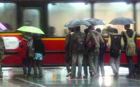 People take shelter under umbrellas from the rain as they cross the road at ITO in New Delhi on Sunday evening
