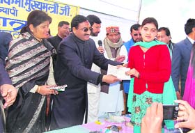 Chief Minister Ramesh Pokhriyal Nishank gives a cheque to a government scheme beneficiary in Champawat