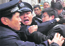 Policemen arrest a man after Internet social networks called to join a Jasmine Revolution protest in front of the Peace Cinema in downtown Shanghai on Sunday