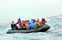 a group rides a raft to the colony of penguins