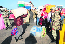 A soldier stands guard as Egyptians carrying their belongings return home from Libya on Tuesday