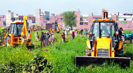JCB machines destroying the standing crop on a piece of land, which the officials attempted to take possession of for, the 45.57 acre scheme of the Improvement Trust in Bathinda on Thursday.