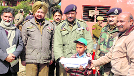 Jagjit Kumar, DIG, Udhampur-Reasi Range, gives a uniform to a student of Government Middle School, Jakhani, in Udhampur on Saturday.
