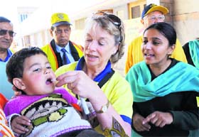 Bernice Yates of Rotary International from the UK administers polio drops to a child in Karnal