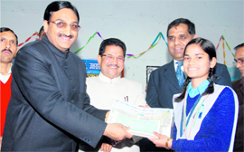 Chief Minister Ramesh Pokhriyal Nishank presents a cheque to a student in Dehradun on Monday.