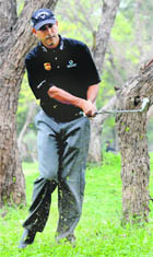 Jeev Milkha Singh, who is playing on the home turf after a gap of 10 years, plays a drive to get out of a tricky situation between trees on the opening day of the