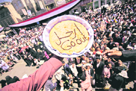 An anti-government protester passes a cake baked by a female demonstrator which reads Leave in Arabic, in Sanaa,
