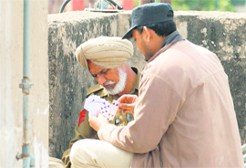 Two securitymen engage in a game of cards on the rooftop of a house near the stadium.