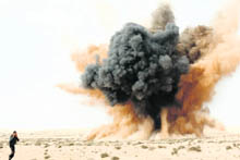 A rebel holds his ears as a bomb launched by a Libyan air force jet loyal to Libya's leader Muammar Gaddafi explodes in the desert near Brega on Wednesday. 