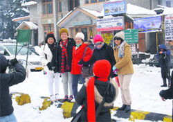 Foreign tourists enjoy snow on the Mall road in Manali on Friday
