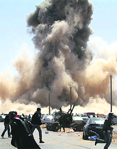 Libyan rebel fighters take cover as a bomb dropped by an airforce fighter jet explodes near a checkpoint on the outskirts of the oil town of Ras Lanuf on Monday.