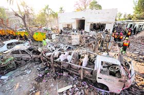 Pakistani rescue workers search for victims among rubble and vehicle wreckage at the scene of a car bomb blast in Faisalabad