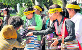 Tibetan women give alms to a beggar during a rally at the Gandhi Park in Dehradun on Thursday.