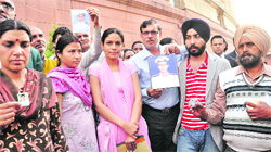 Relatives of Indian sailors held hostage by Somali pirates hold up pictures of their loved ones outside Parliament in New Delhi