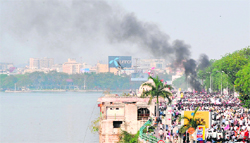 Pro-Telangana activists walk in front of a burning vehicle in Hyderabad